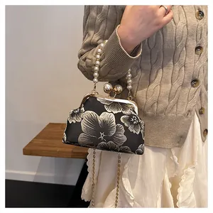 Detail of floral embroidery on black silk bag with large pearl handle and metal clasp
