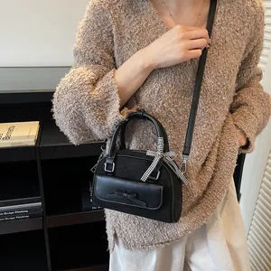 Bolso de mano retro de gamuza negra estilo universitario con lazo y cinta en el asa