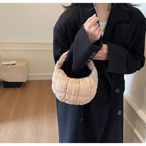 Detail of beige quilted puffer underarm bag with zipper closure and padded handle