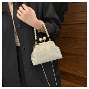 Detail view of light green floral embroidery bag with pearl handle and metal chain strap