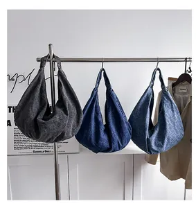 Close-up of crescent denim tote bags in dark grey, dark blue, and medium blue colors