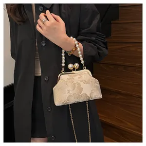 Detail of floral jacquard fabric and pearl handle on shell-shaped crossbody bag