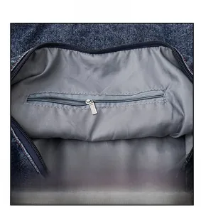 Detail shot of the interior zipper pocket and dark blue denim fabric of the tote bag
