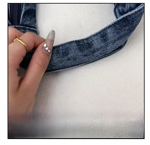Detail of dark blue denim tote bag with brown stitching and wide handle strap