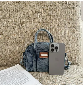 Micro denim Boston handbag showing mini size scale next to a smartphone