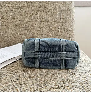 Close-up of the denim handbag bottom showing reinforced stitching and washed texture