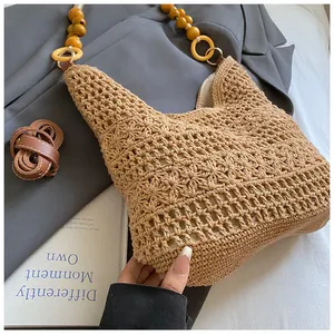 Detail of hollow woven straw tote bag featuring beaded strap and leather shoulder strap