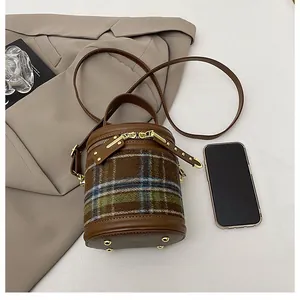 Detalle del mini bolso cilindro con paneles de lana a cuadros y herrajes dorados