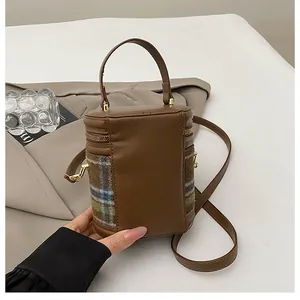 Detalle del bolso de cubo vintage en cuero marrón con lana a cuadros y herrajes oro