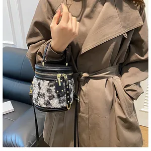 Detalle del bolso tipo cubo de leopardo con ribete de cuero usado por modelo en abrigo