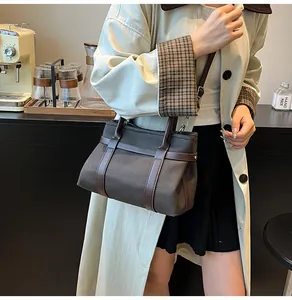 Dark grey canvas tote bag with brown leather straps in a cozy cafe setting