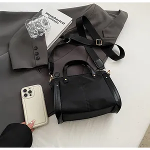 Detalle del bolso tote de nailon negro con correa ancha ajustable y herrajes dorados