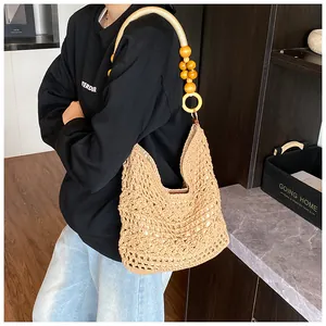 Detail of hand-woven straw tote bag featuring wooden rings and yellow beaded handle