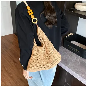 Detailed close-up of woven straw tote bag featuring decorative beads and hollow texture