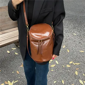 Bolso cubo marrón de textura esmerilada con flecos, mostrado como bolso bandolera