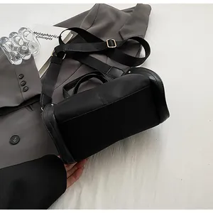 Detalle de bolso tote negro de nailon con correa ancha y hebillas de metal dorado