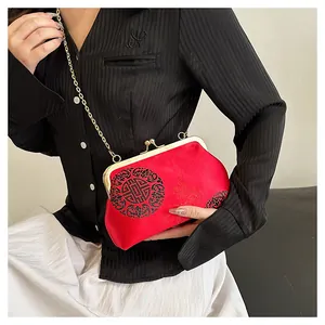 Detail of red satin shell bag featuring traditional black dragon patterns and gold chain