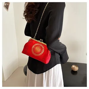 Detail of red silk crossbody bag with golden embroidery and metal chain strap