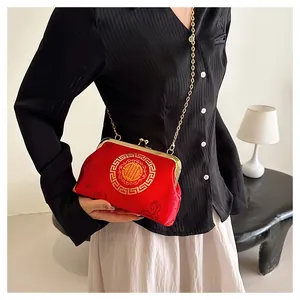 Detail of red brocade chain bag featuring golden embroidery and metallic frame