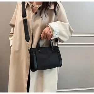 Modelo con bolso tote de nailon negro con bandolera ancha y gabardina color beige