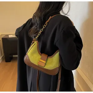 Detalle del bolso de ante verde aguacate con cuero marrón y correa de cadena dorada