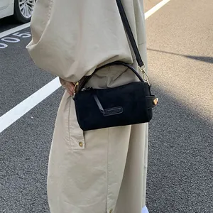 Bolso de mano negro mate con herrajes dorados y logo PANTOR llevado con gabardina casual