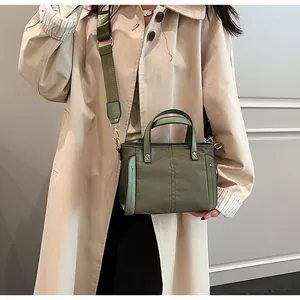 Detalle del bolso tote de nailon verde militar con correa ancha y adornos de cuero