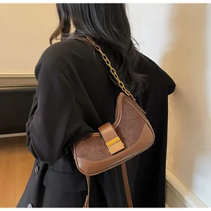 Vista detallada del bolso bajo el brazo en ante y cuero marrón con cadena dorada