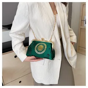 Close-up of emerald satin shell bag with traditional patterns and gold chain