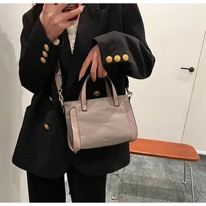Detalle de bolso tote de nailon gris con ribete de cuero rosa y remaches metálicos a la moda