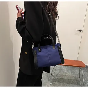 Bolso tote de nailon azul oscuro con asas negras y correa de hombro en escena de estilo