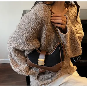 Detalle de bolso de ante con cadena dorada y cierre de hebilla metálica vintage