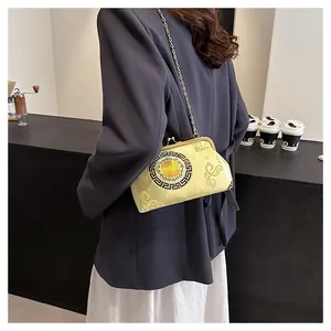 Detailed view of yellow satin crossbody bag with cloud embroidery and gold chain