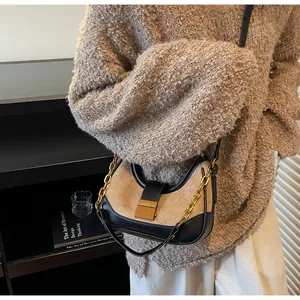 Vista detallada del bolso hobo de ante con hebilla dorada y cadena sobre modelo