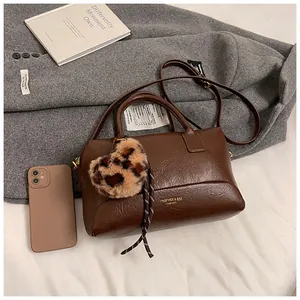 Vue détaillée d'un sac à main en cuir marron grainé avec un charme cœur léopard
