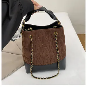 Detalle de bolso cubo vintage acolchado de ante marrón y detalles de cuero negro