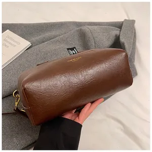 Détail du sac à main en cuir marron rétro avec lettrage doré et texture grainée