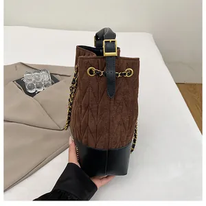 Detalle del bolso de cubo acolchado marrón con cadena dorada y textura de gamuza