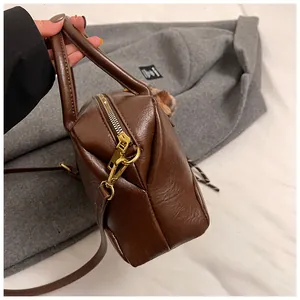 Détail d'un sac à main en cuir marron foncé avec ferrures dorées et fini texturé