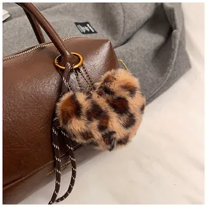 Détail d'un porte-clés coeur en peluche léopard avec anneau doré sur un sac à main en cuir