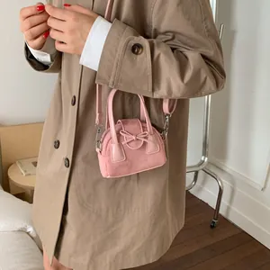 Mini bolso bandolera rosa con lazo decorativo y detalles en ante y cuero liso