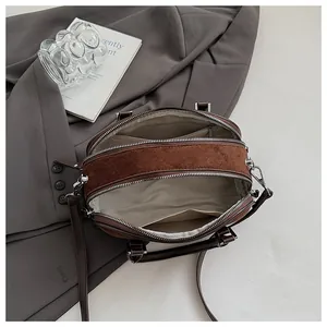 Vista detallada del interior del bolso marrón con compartimentos dobles y textura mate suave