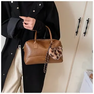 Détail d'un sac en cuir PU marron avec breloque léopard et corde tressée décorative