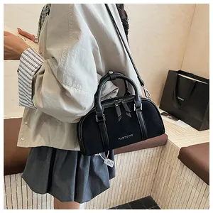 Detalle del bolso Boston negro de ante con asas dobles y herrajes metálicos plateados