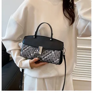 Détail d'un sac à main tissé bicolore avec fermoir rotatif argenté et bandoulière