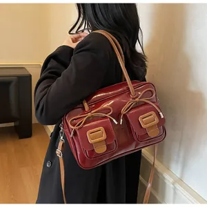 Detail of burgundy glossy handbag featuring brown bow drawstrings and front flap pockets