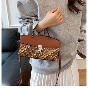 Détail du sac tissé vintage avec rabat en cuir marron et fermoir métallique élégant
