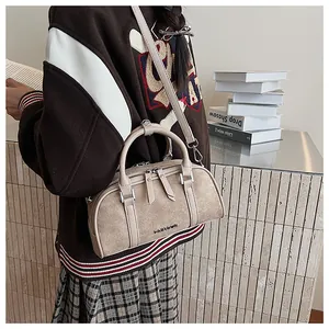 Detalle de bolso baguette beige vintage con cremallera doble y correa ajustable