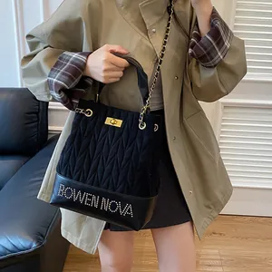 Bolso cubo negro acolchado con cadena dorada y letras con incrustaciones de diamantes