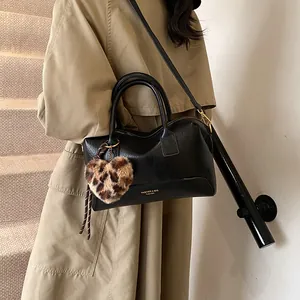 Sac Boston noir chic avec breloque cœur léopard porté par un mannequin